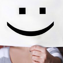 person holding up a smiley face sign