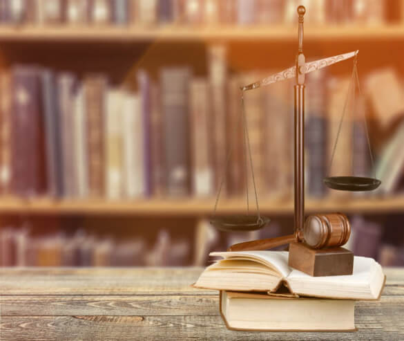 A weight scale, a judges gavel, and law books on a desk